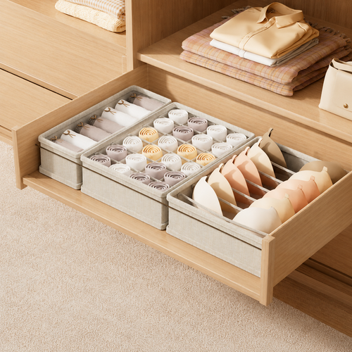 Open wooden drawer with three fabric compartment organizers holding neatly arranged socks, underwear, and bras.