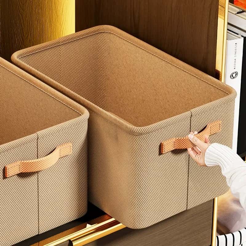 Brown fabric closet storage bins with fitted lids and side handles, with a person pulling one from a shelf.